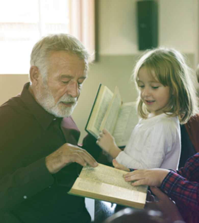 Elderly man reading a book to attentive children