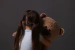 sad child holding teddy bear