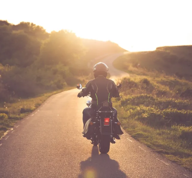 Motorcycle rider on the road in sunset light. Travel and sport, speed and freedom concept.