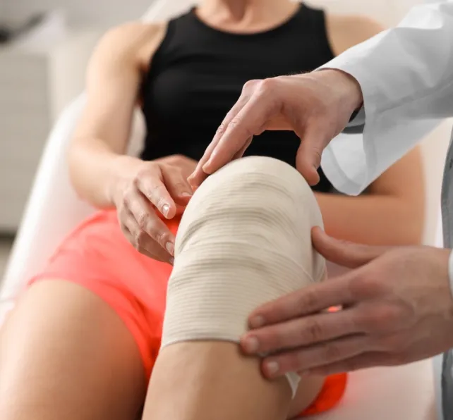Sports injury. Doctor examining patient's knee in hospital, closeup