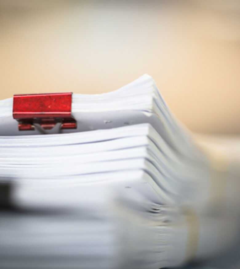 Stack of organized documents secured with a red binder clip