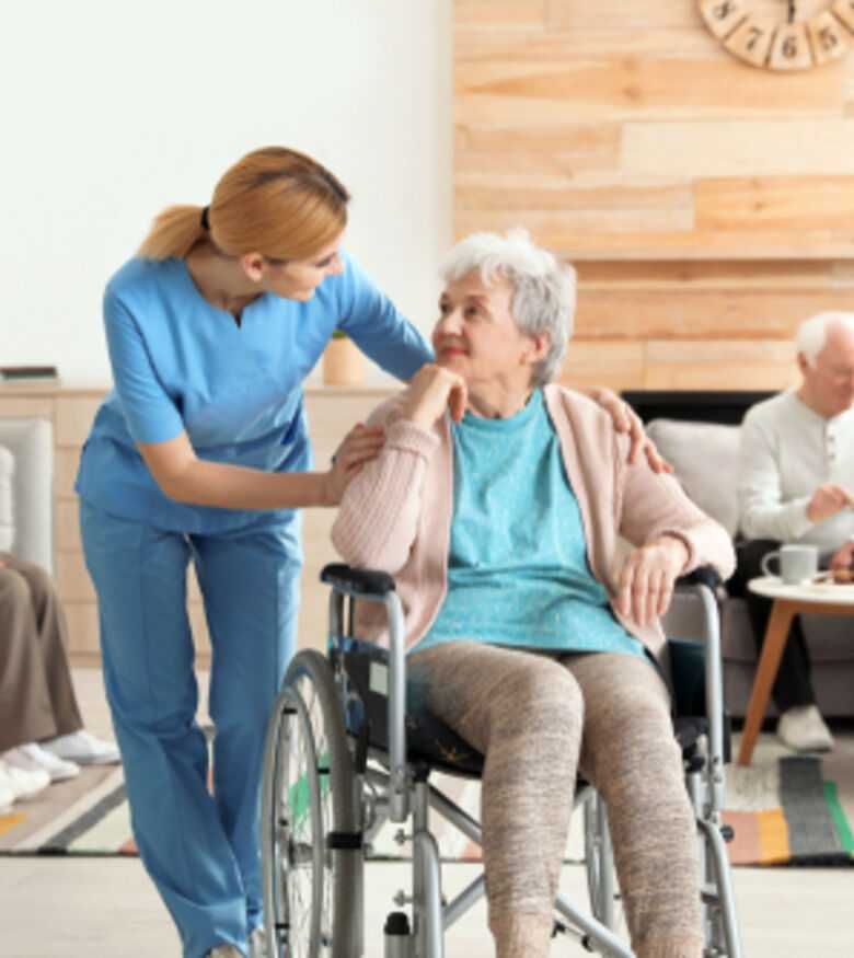 Compassionate caregiver assisting senior woman in wheelchair at a nursing home 