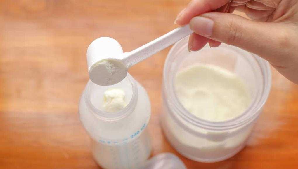 putting baby formula into a baby bottle