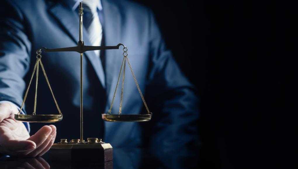 Man in suit holding a balance scale with dark background