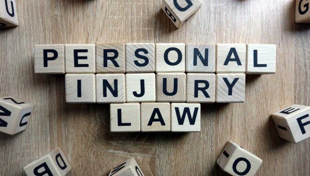 Personal Injury Law text spelled out with wooden letter blocks on a wooden table background.