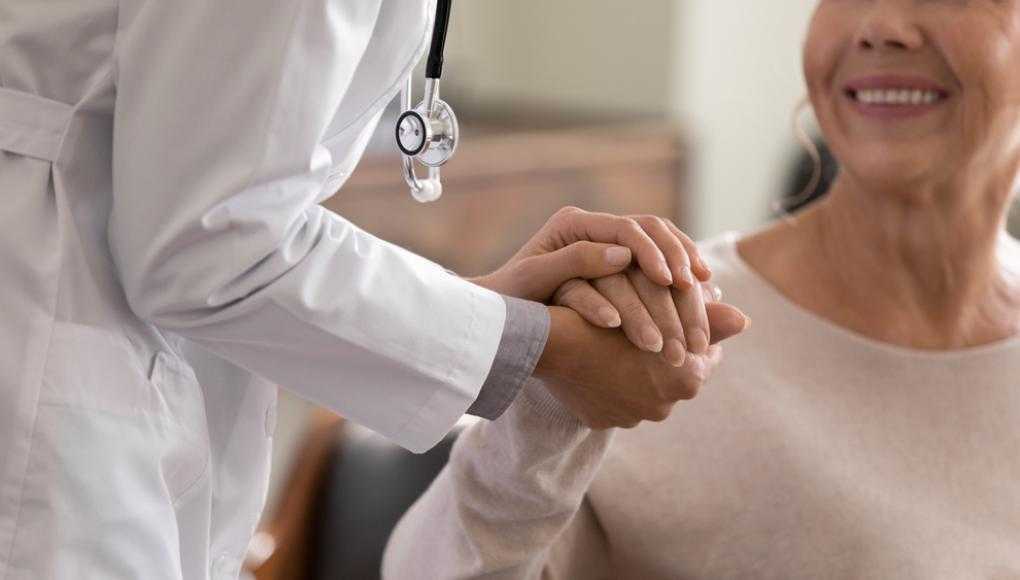 Doctor holding hands with a smiling patient, providing compassionate care and support