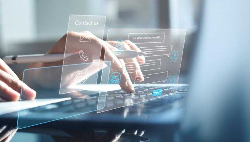 Close-up of hands typing on a laptop with digital customer service interface hologram.