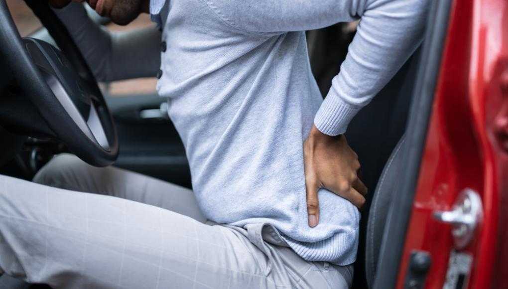 Man holding back in pain sitting in a car