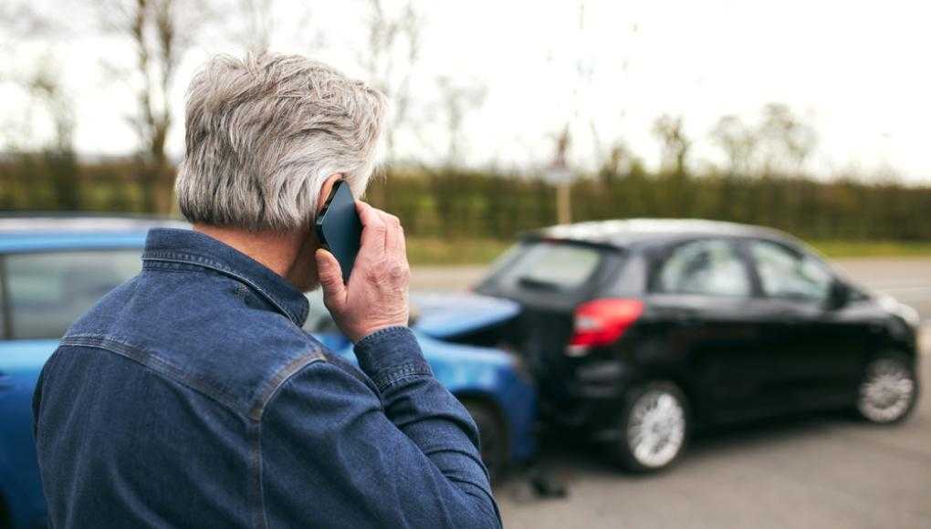 Man on the phone in front of two cars after an accident