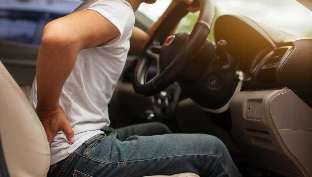 Man holding back in pain sitting in a car