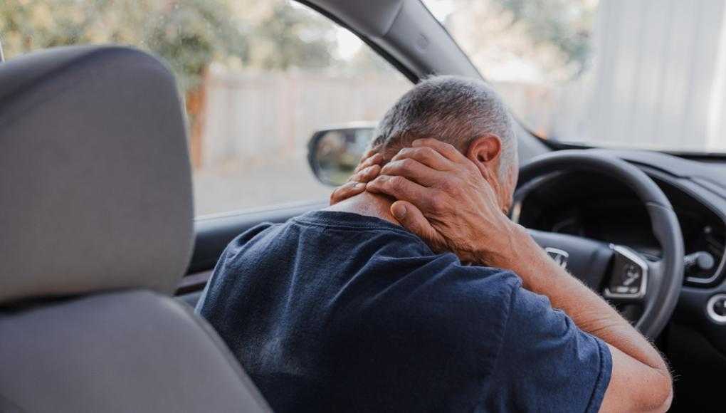 Man holding back in pain sitting in a car