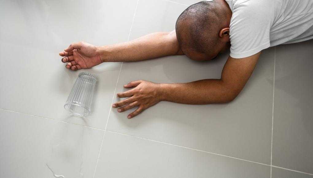 Man fallen down on the floor with a spilled cup of water