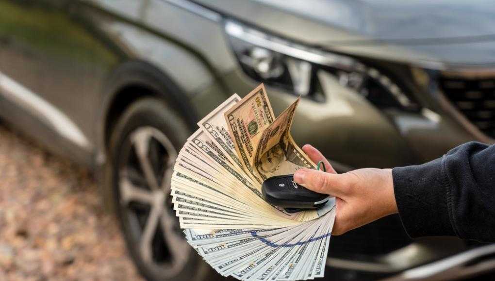 Person fanning money in front of a car with keys