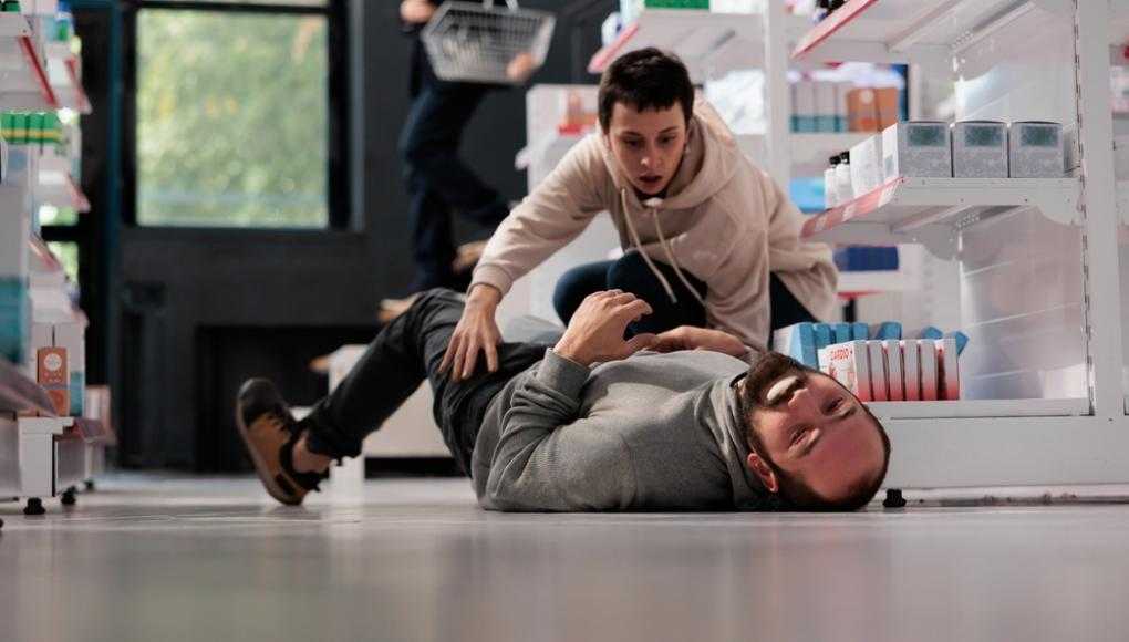 Women helping man who fell on the floor of a store