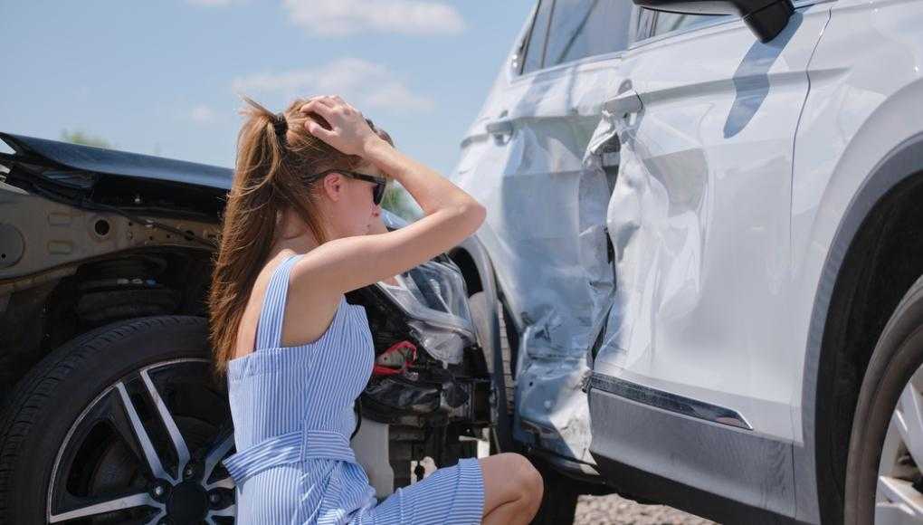 Woman in distress looking at her car after an accident