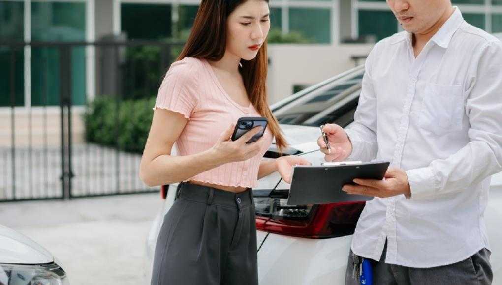 Two people discussing paperwork after a car crash