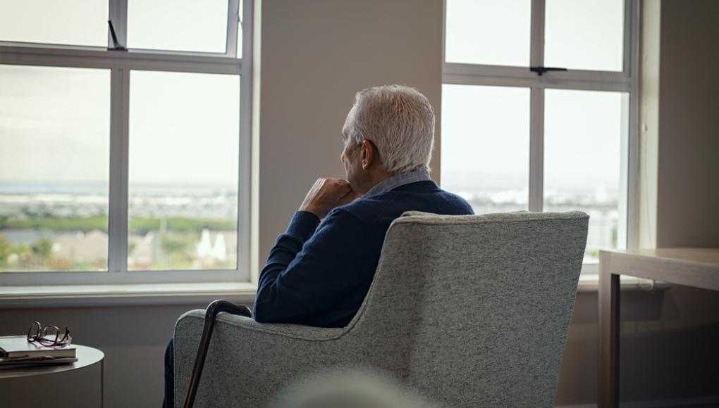 older man sitting at the window of a nursing home