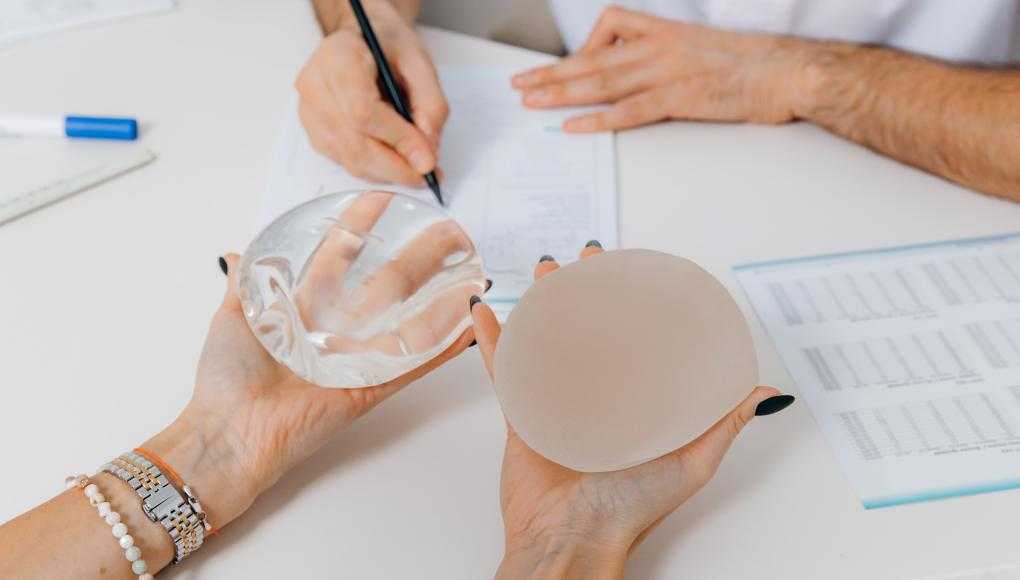 Someone holding two different breast implants