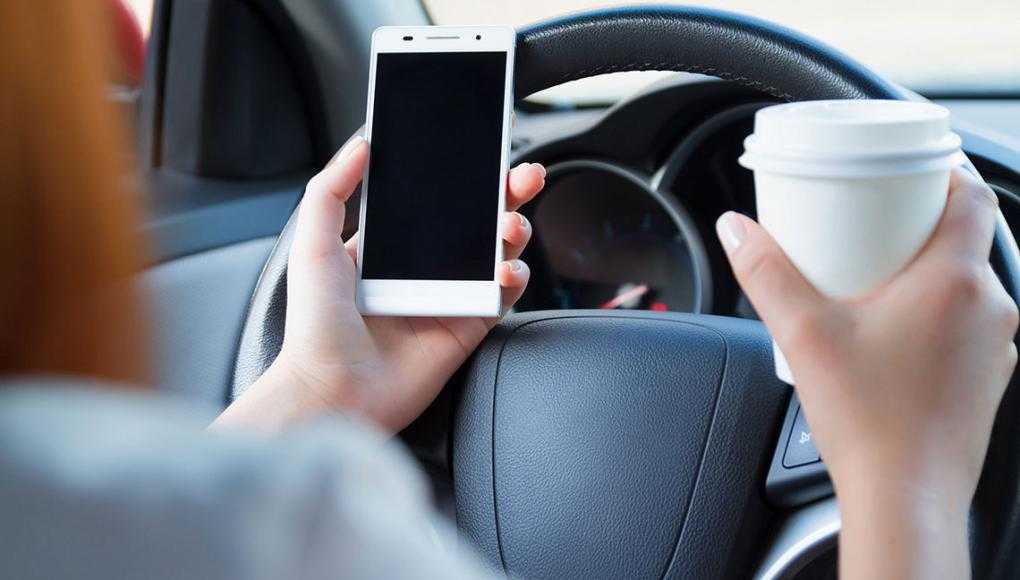 What is Tennessee Doing to Combat the Rise of Distracted Driving? - A man in a car with a cup of coffee and mobile phone