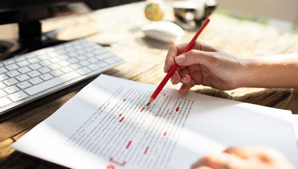 Close-up Of A Person's Hand Marking Error With Red Marker On Document