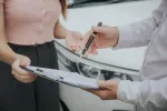 two people reviewing insurance claim with car in background