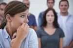 person nervously looking away with people behind them, staring at them