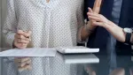 two people sitting with one person putting their hand up to block the other one from touching them