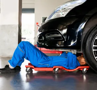 Mechanic wearing a blue jumpsuit working under a car