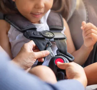 child putting on their seatbelt