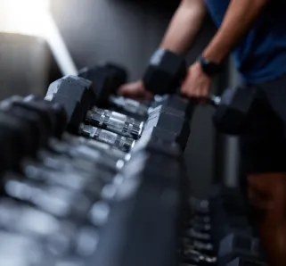 trainer putting heavy weights back on shelf
