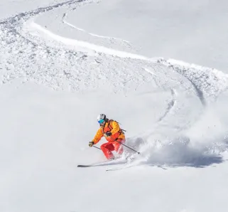 one freeride skier skiing downhill trough deep fresh powder