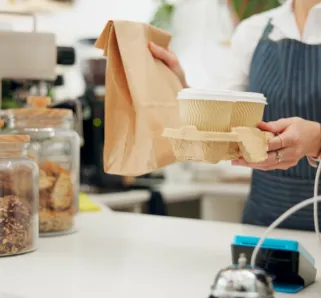 Barista, customer and takeaway coffee or giving at counter as breakfast order, morning or espresso. Person, hands and cafe shop or lunch beverage for small business food at bakery, latte or drink