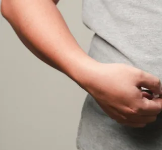person standing with a grey shirt and a measuring tape