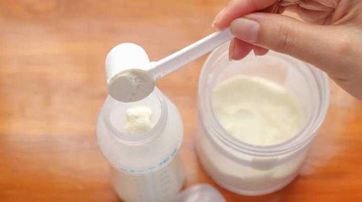 putting baby formula into a baby bottle