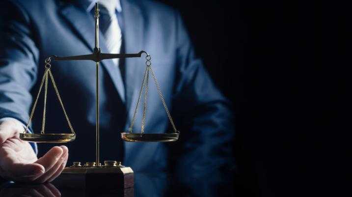 Man in suit holding a balance scale with dark background