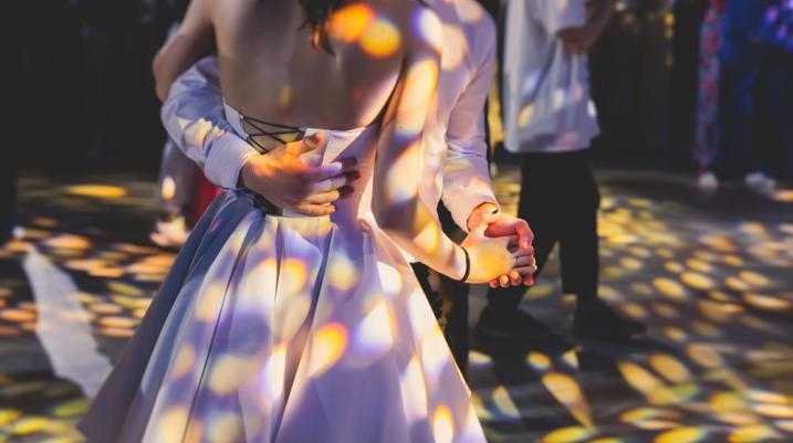 Teenagers dancing at prom night under colorful lights