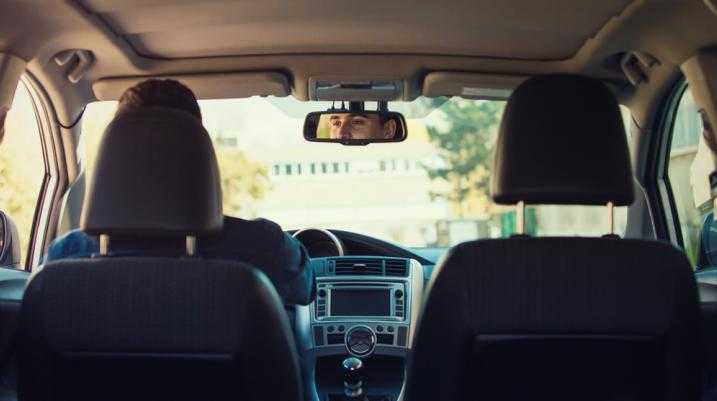 View from the backseat of a car facing the driver