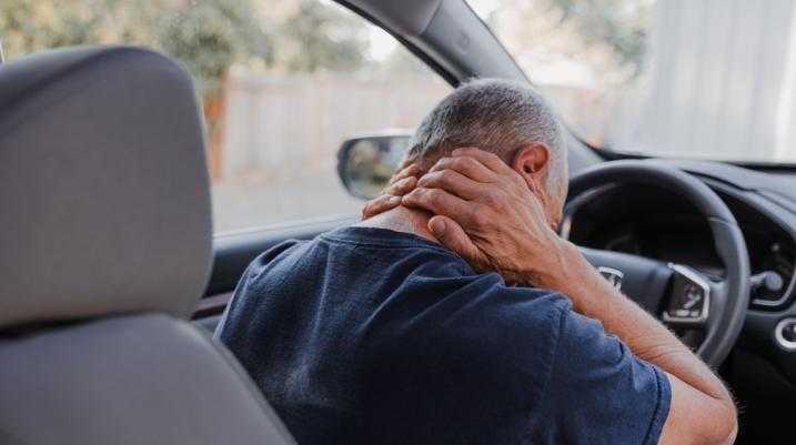 Man holding back in pain sitting in a car