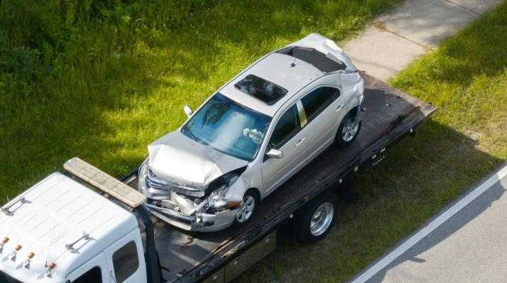 Damaged car on the back of a semi truck bed