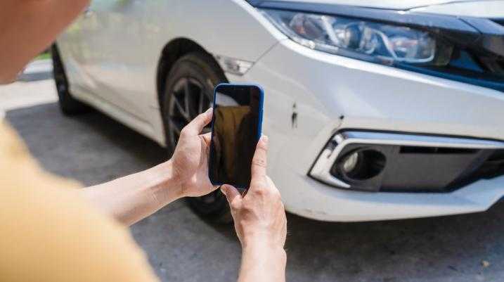 Man taking a picture of a damaged car