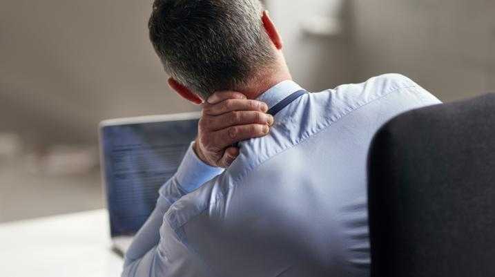 Man at his desk holding his neck in pain