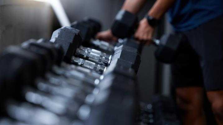 trainer putting heavy weights back on shelf