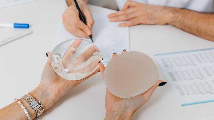 Someone holding two different breast implants