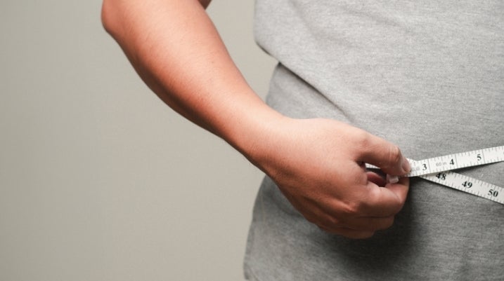 person standing with a grey shirt and a measuring tape