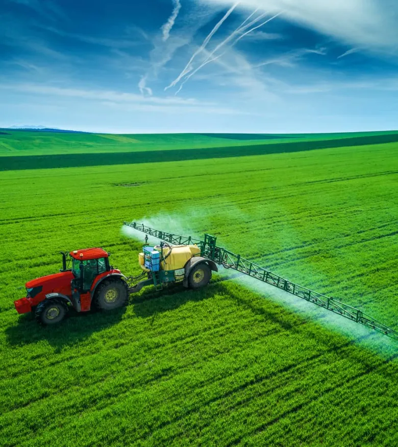 Aerial view of farming tractor plowing and spraying on field.