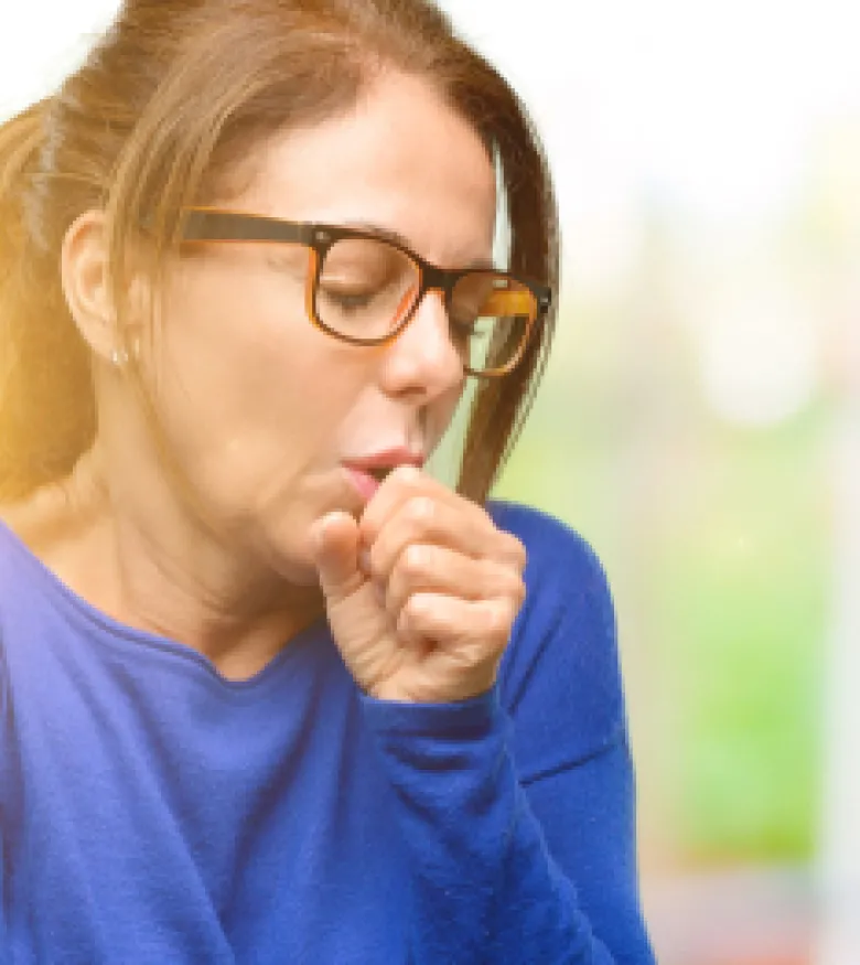 A woman coughing and appearing unwell, highlighting the need for a Mesothelioma Attorney in Queens to provide legal assistance.