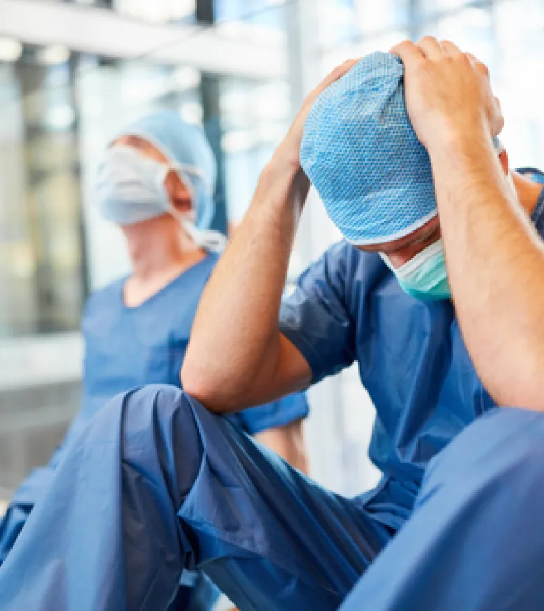 Two distressed surgeons sitting on the floor, emphasizing the need for a Medical Malpractice Attorney in Queens to handle legal issues arising from medical errors.