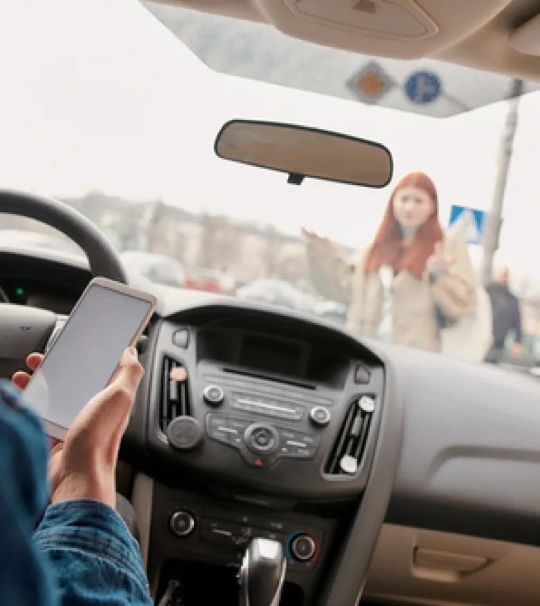 A driver using a phone while a pedestrian is crossing the street, emphasizing the need for a Pedestrian Accident Attorney in Gainesville for legal assistance.