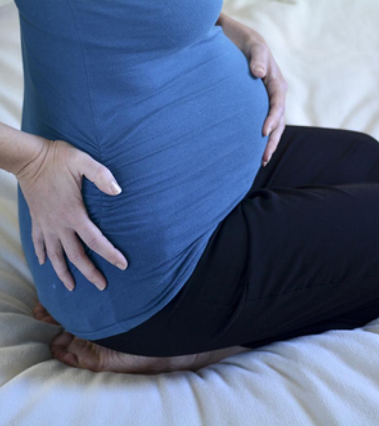 Pregnant woman experiencing discomfort, contact a birth injury lawyer in Queens for support.