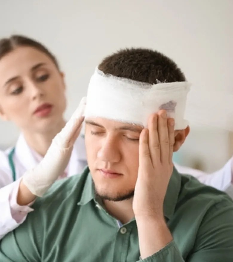 A medical professional bandaging a man's head, highlighting the need for legal assistance for Neck, Spinal Cord, and Back Injury in Bowling Green.